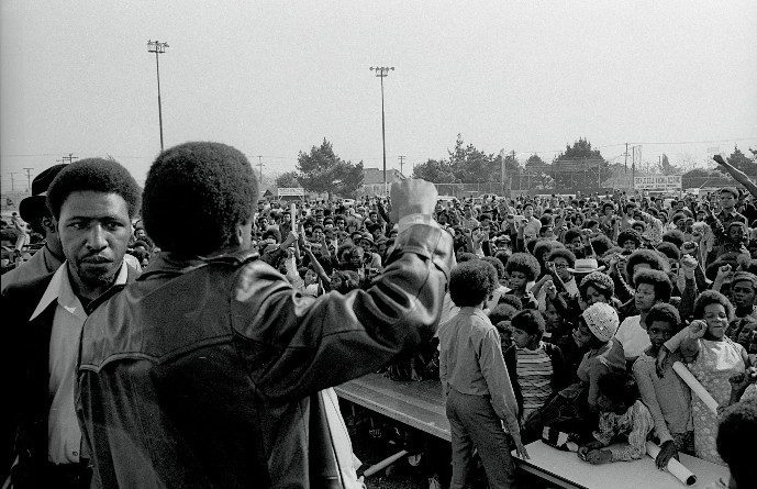 Chico Neblett and Bobby Seale (back) leading audience with a Black Power salute at the Black Community Survival Conference, March 30, 1972 (Bob Fitch Photography Archive, Stanford University Libraries)