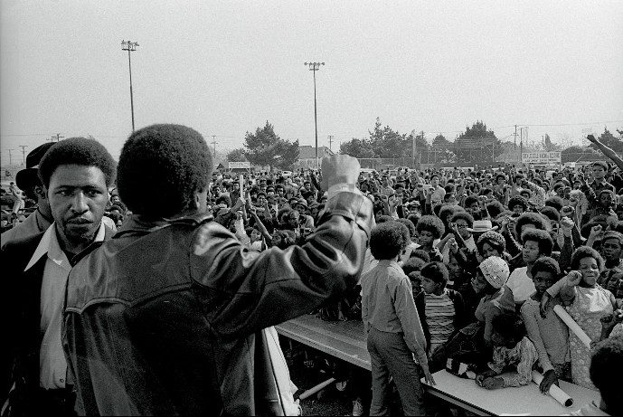 Chico Neblett and Bobby Seale (back) leading audience with a Black Power salute at the Black Community Survival Conference, March 30, 1972 (Bob Fitch Photography Archive, Stanford University Libraries)